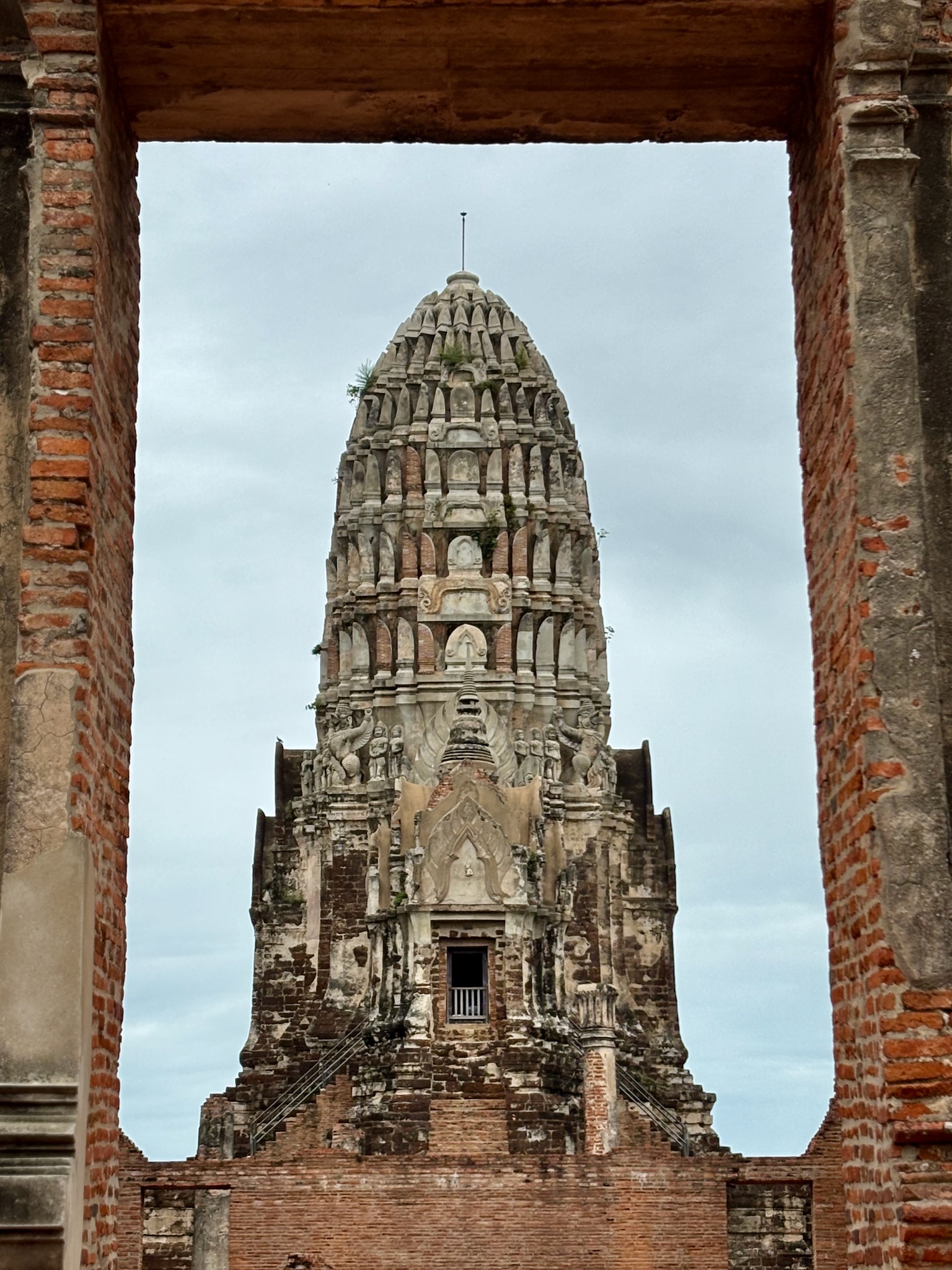 An Ayutthaya prang framed through a brick temple arch