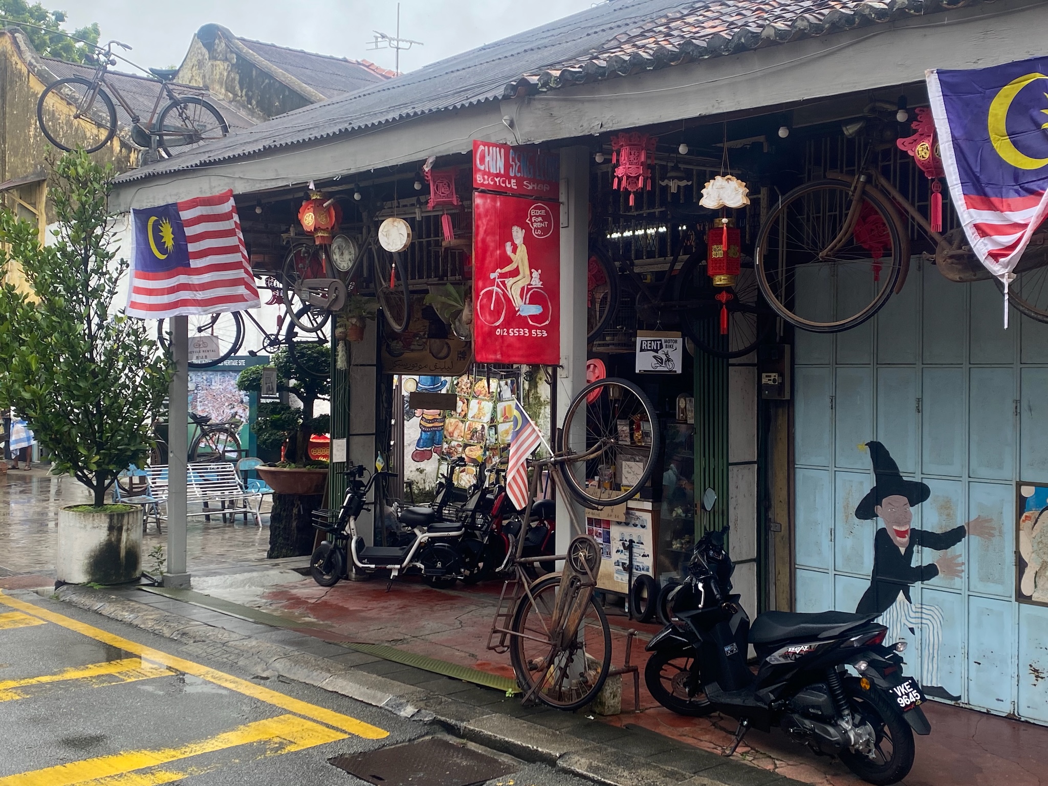 An old Penang bicycle shop hung with wheels and lanterns and a Malaysian flag