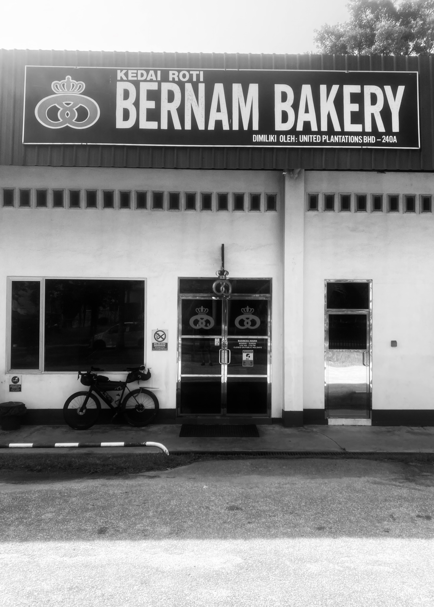 The bike outside Bernam Bakery, a plantation-town storefront, in black and white