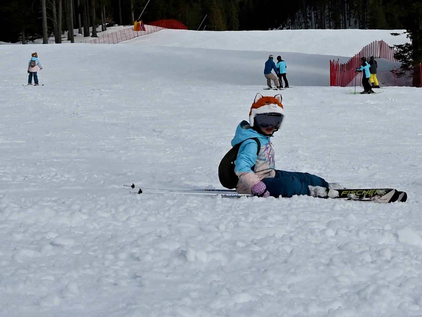 A girl sitting in the snow, still grinning