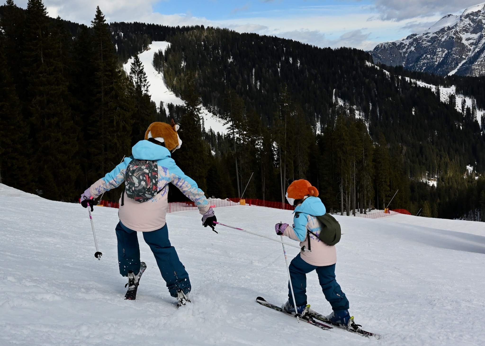 The girls skiing down toward the tree line