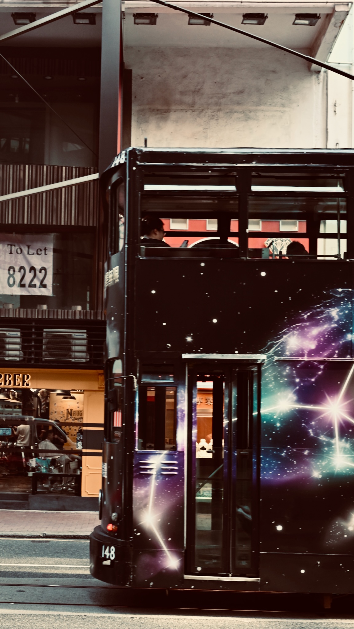 A galaxy-liveried tram passing a barber shop