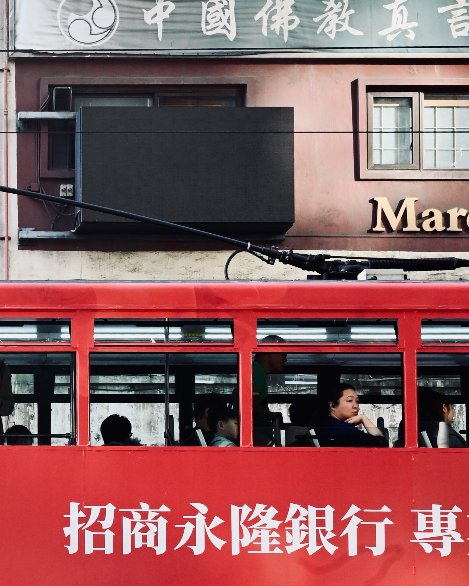 A passenger resting her chin on a red tram