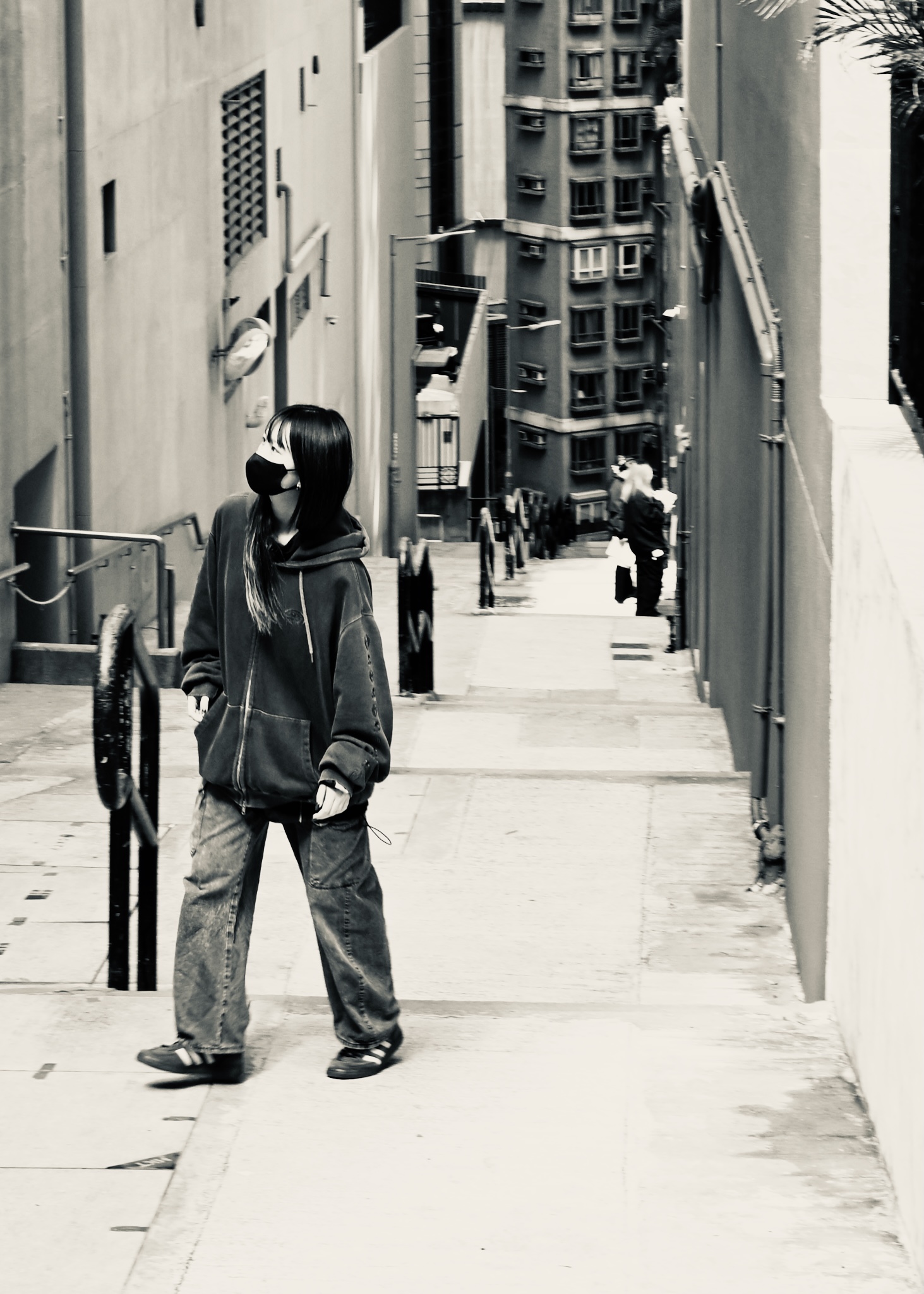 A masked figure on a steep lane, black and white