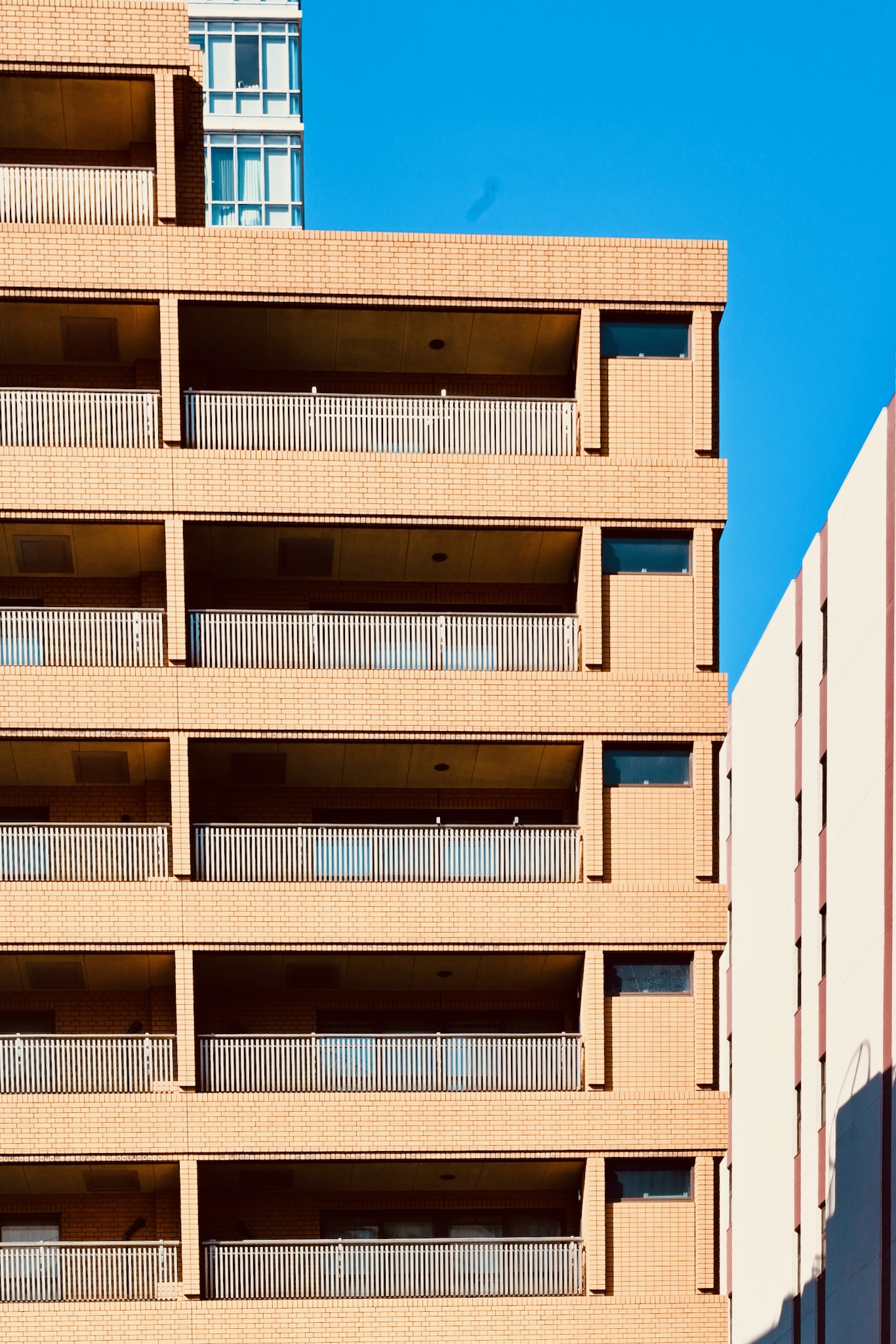 A brick apartment block with deep balconies in morning sun
