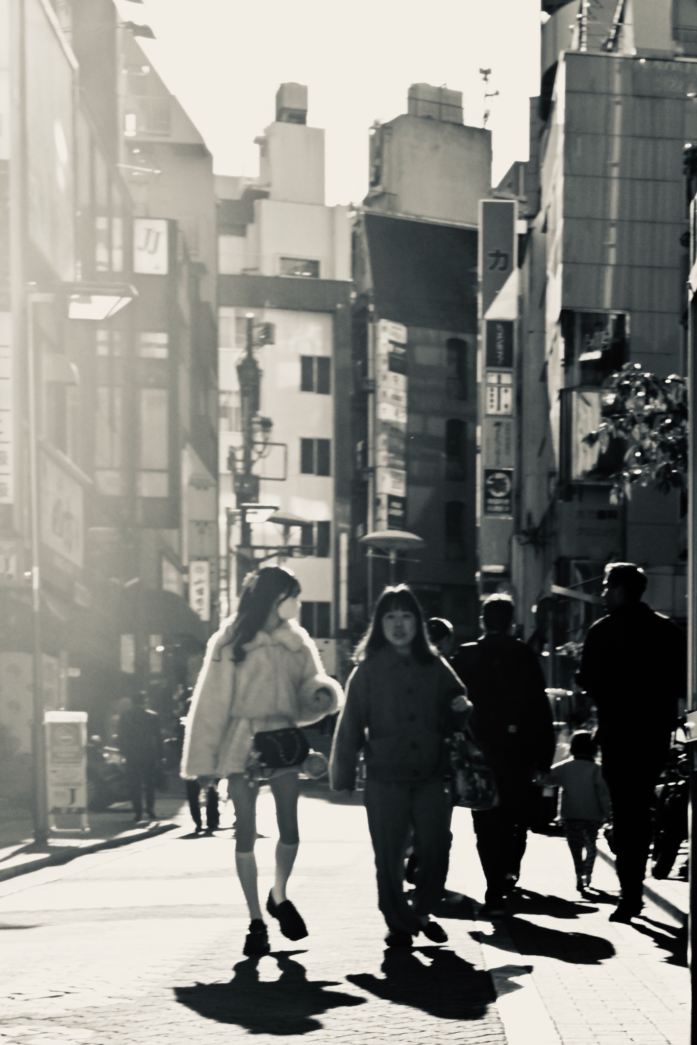 Backlit Tokyo street, two women walking into the sun, black and white