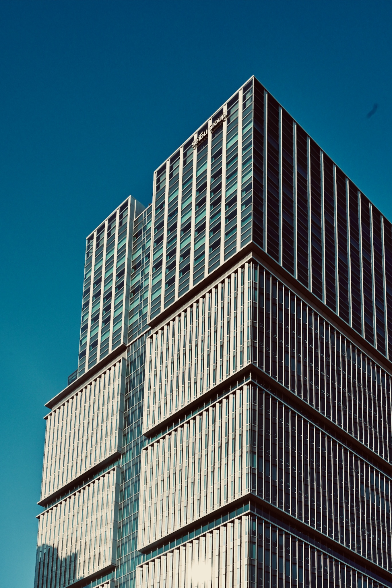 A glass office tower against deep blue sky