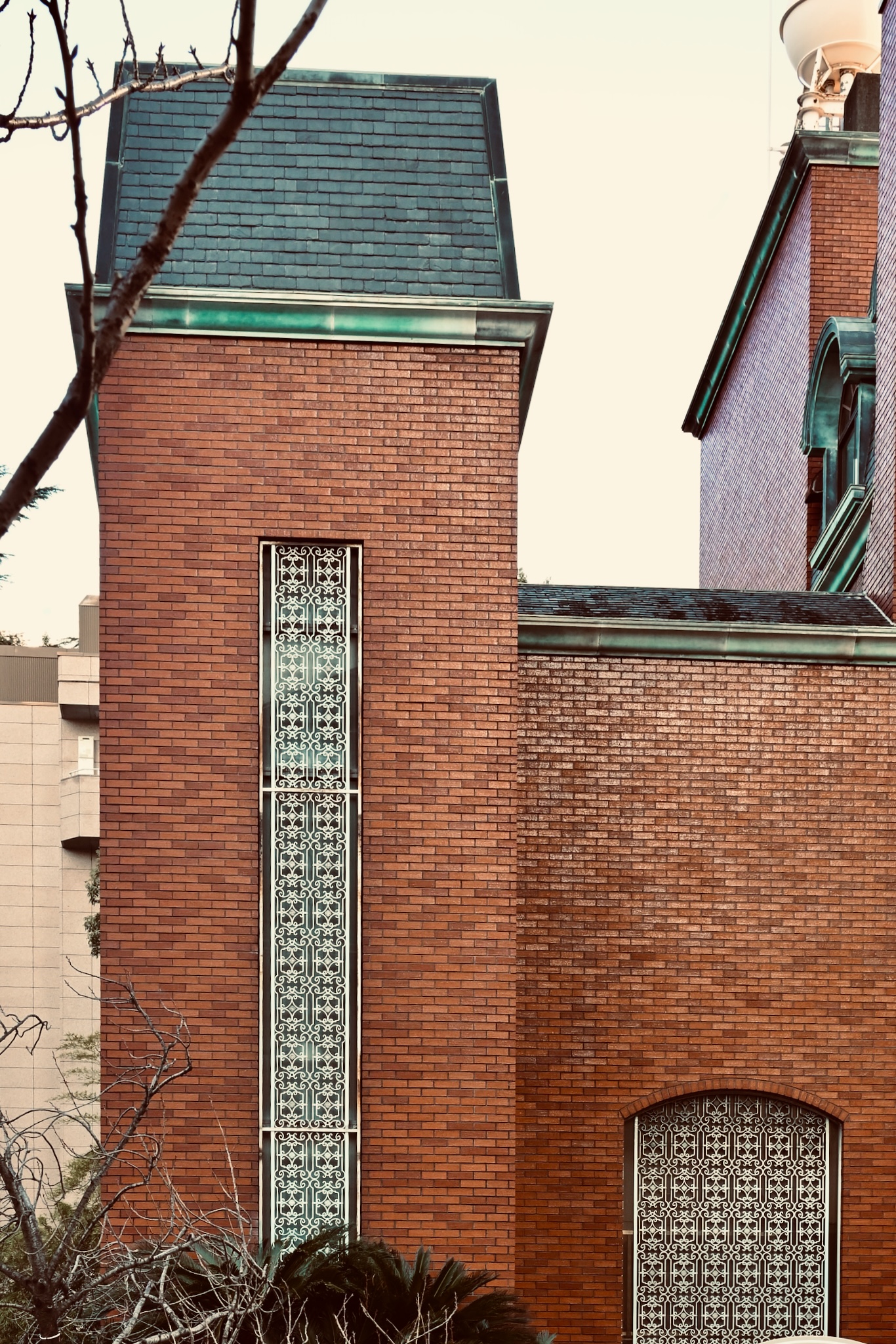 A red-brick tower with ornate ironwork glazing