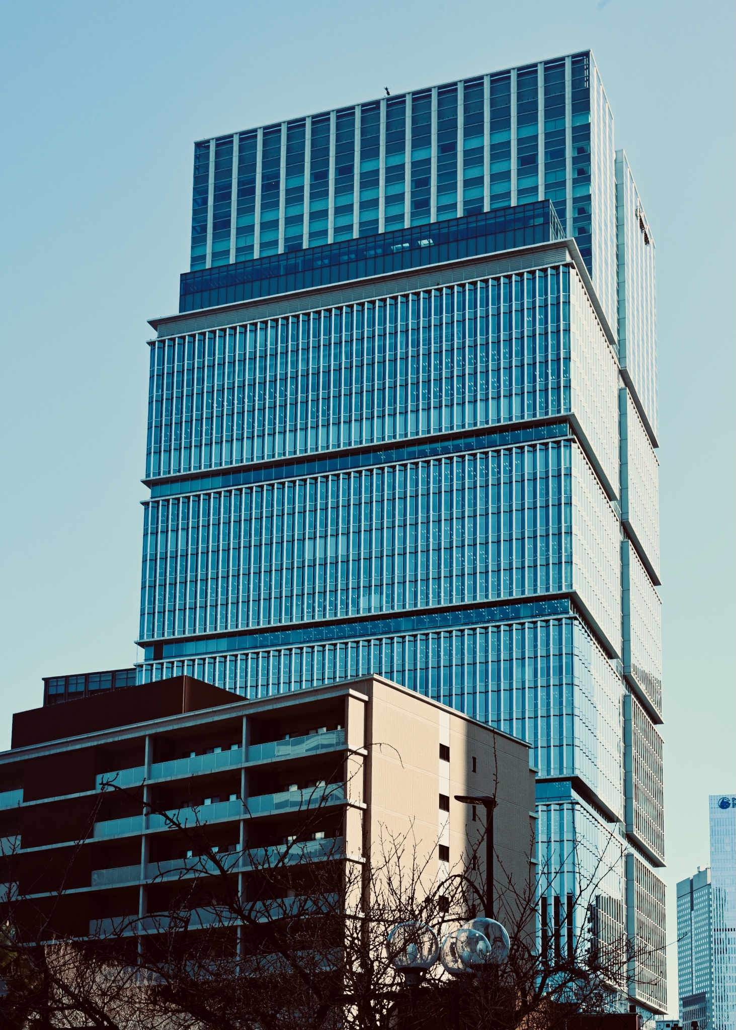 A stacked blue glass tower from below