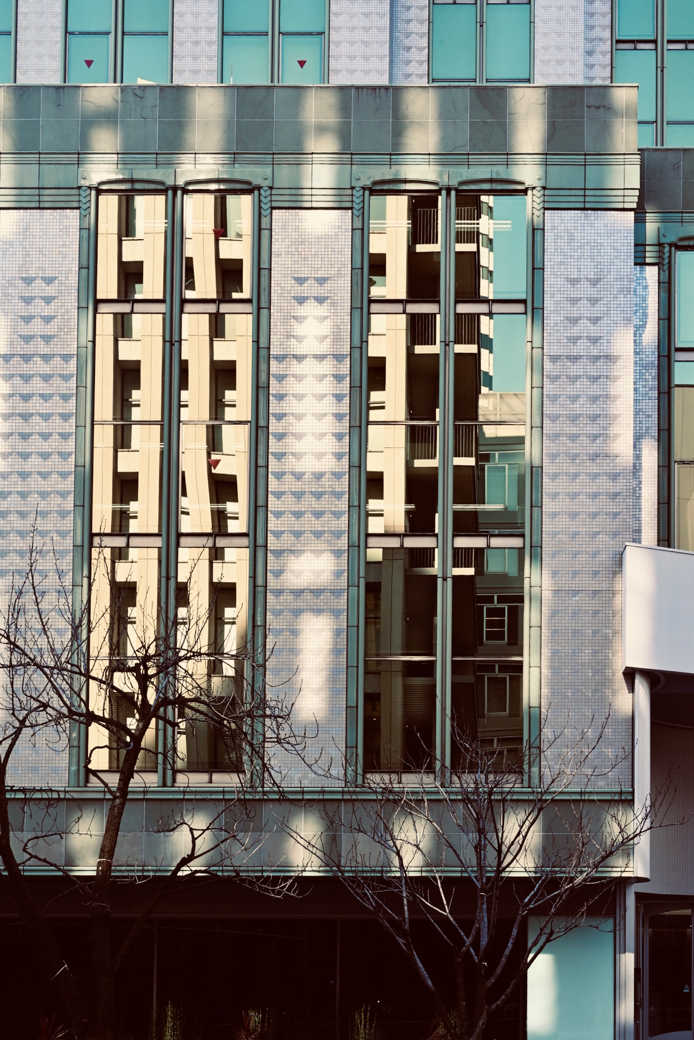 An art-deco tiled facade with tall reflecting windows