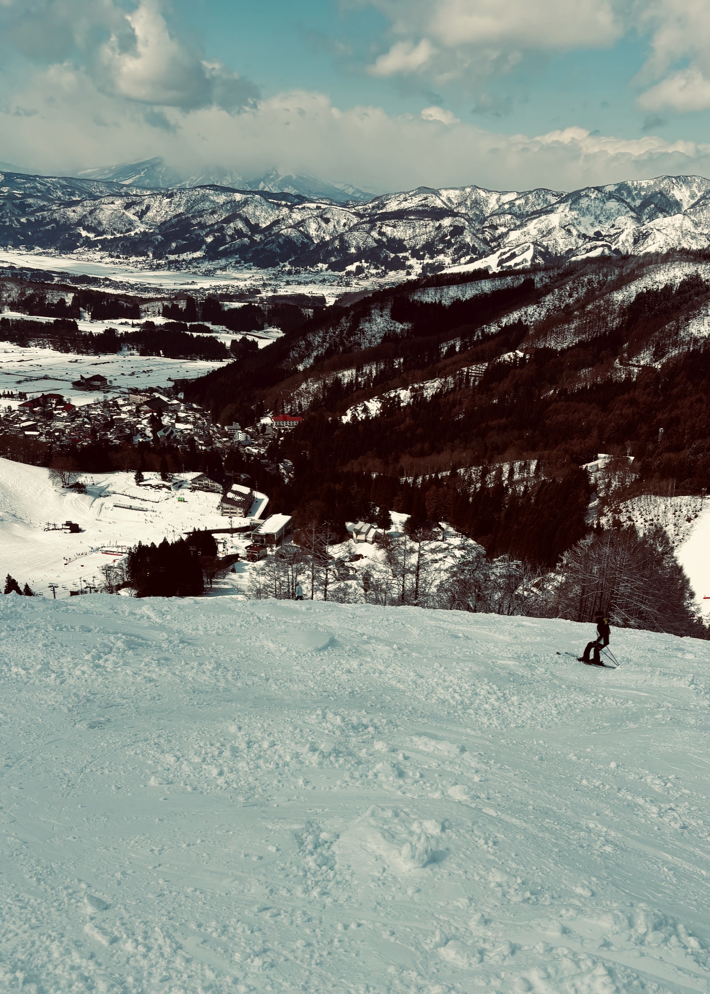 A skier dropping in, the town far below, moody light