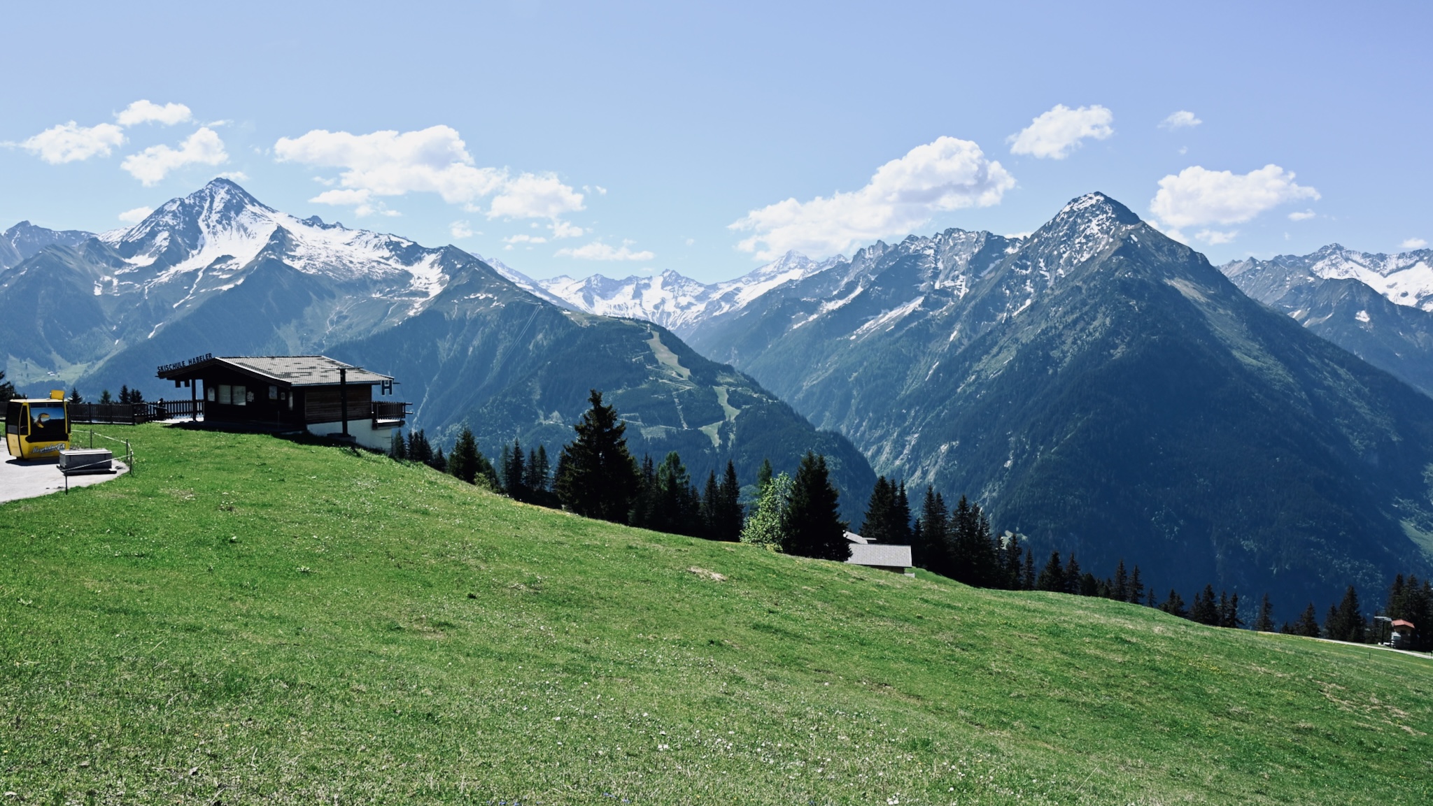A green meadow and a mountain hut below the peaks