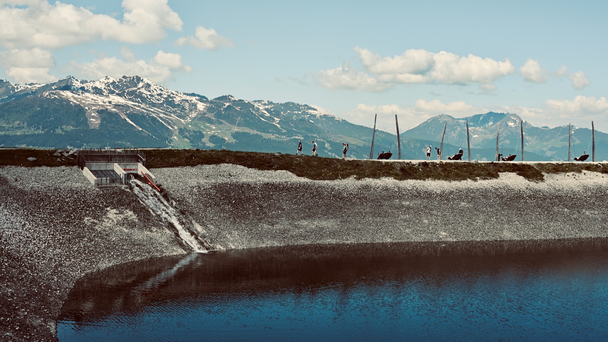 Walkers along a mountain-top reservoir dam