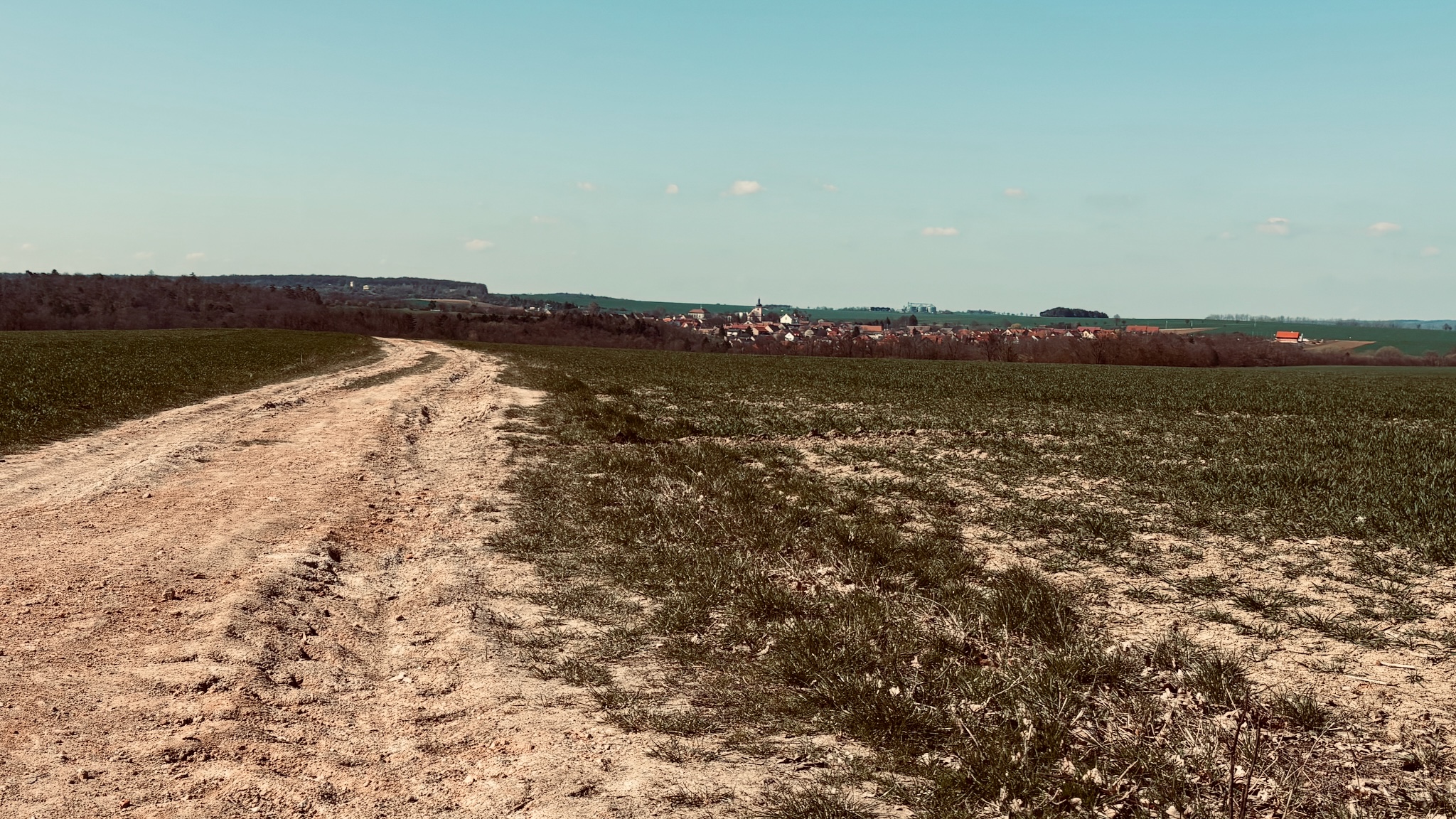 A farm track running out toward distant fields and a village