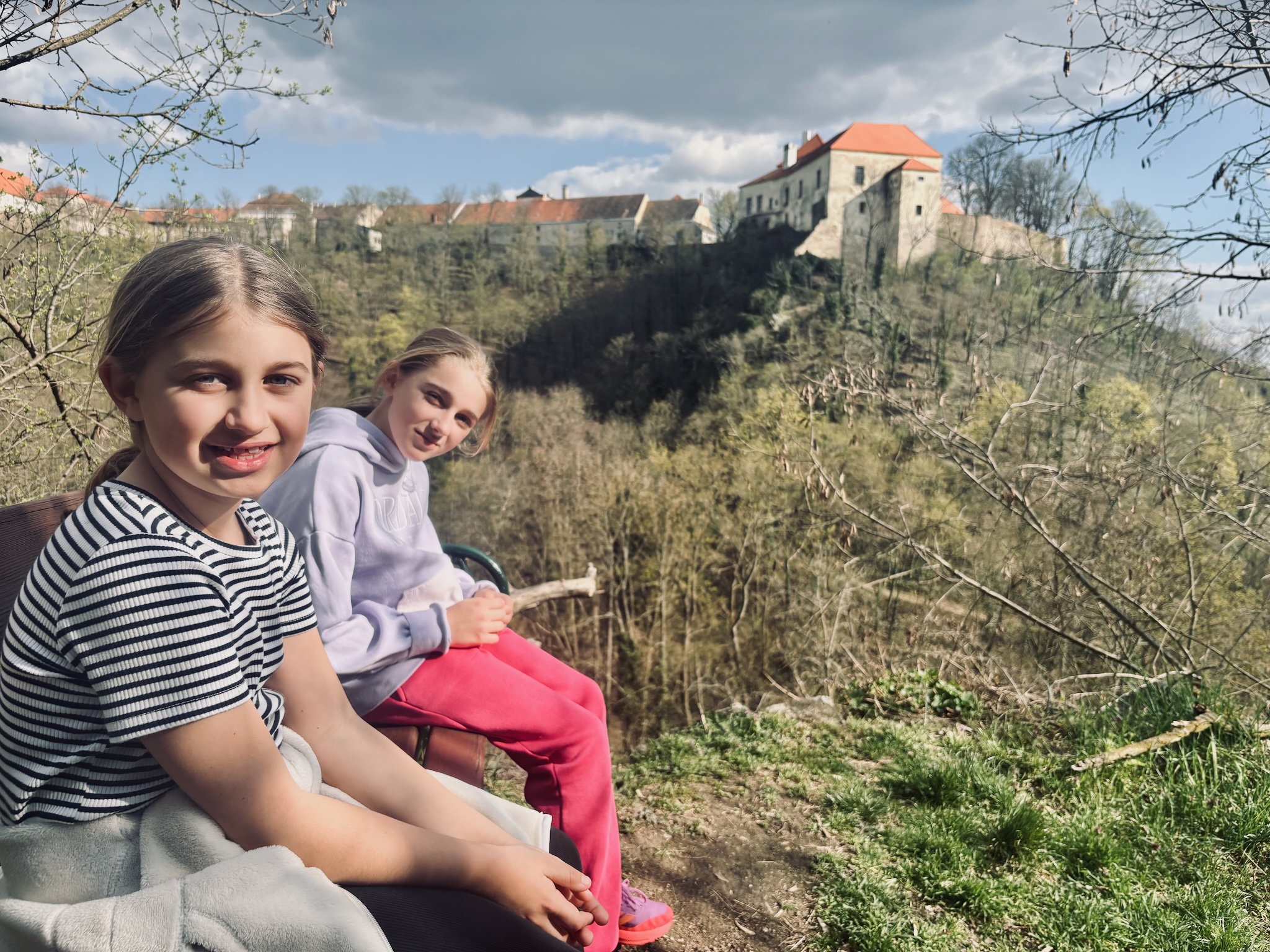 The two girls on a bench, a castle on the ridge behind
