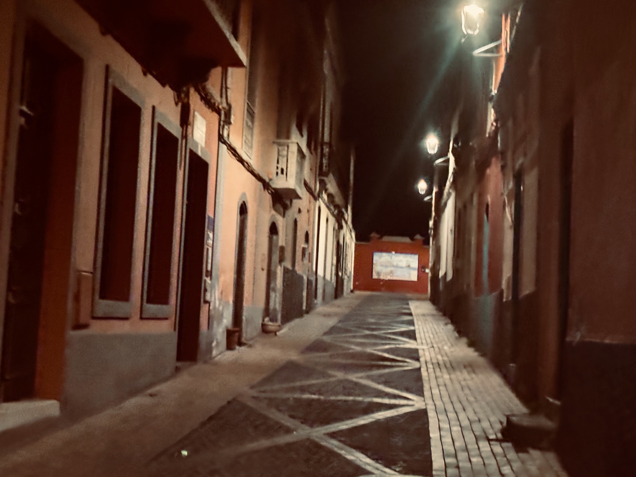 An empty, lamp-lit village alley in the small hours