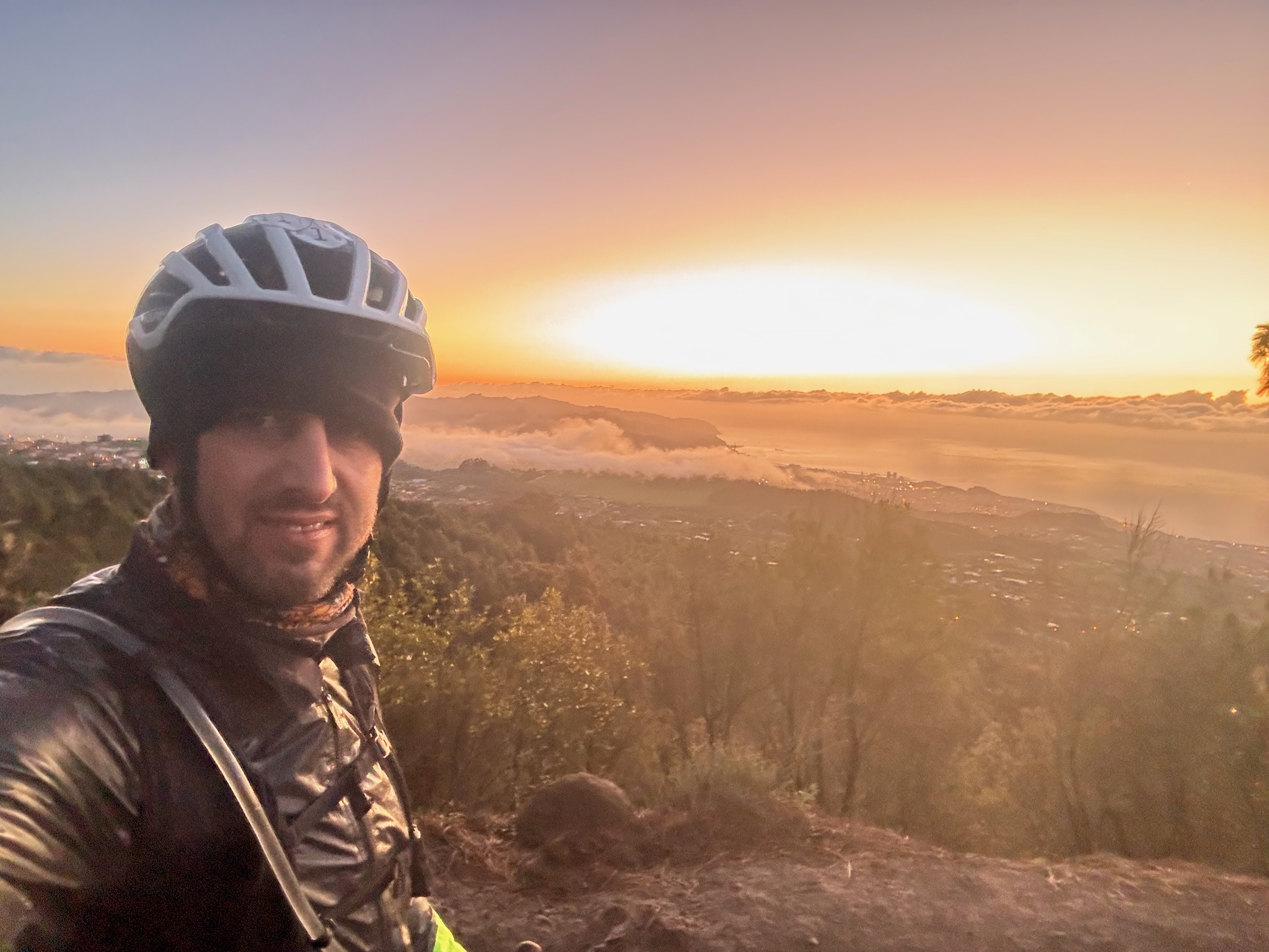 A dawn selfie above a sea of cloud, the sun coming up orange behind