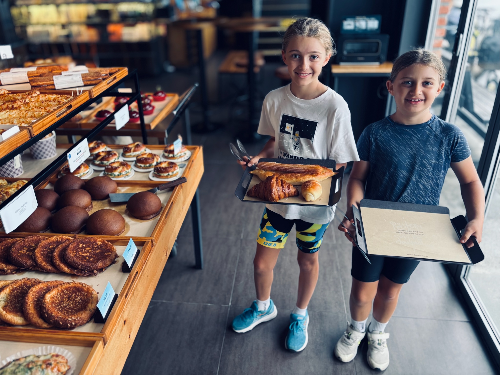 The girls holding trays of pastries in a bakery