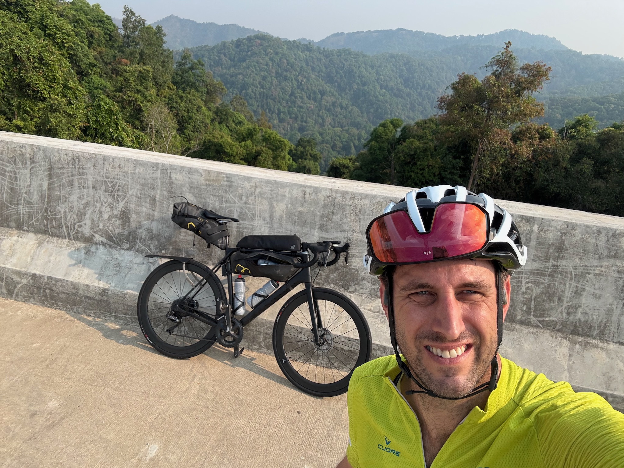 Selfie on a high concrete bridge with green forested hills behind